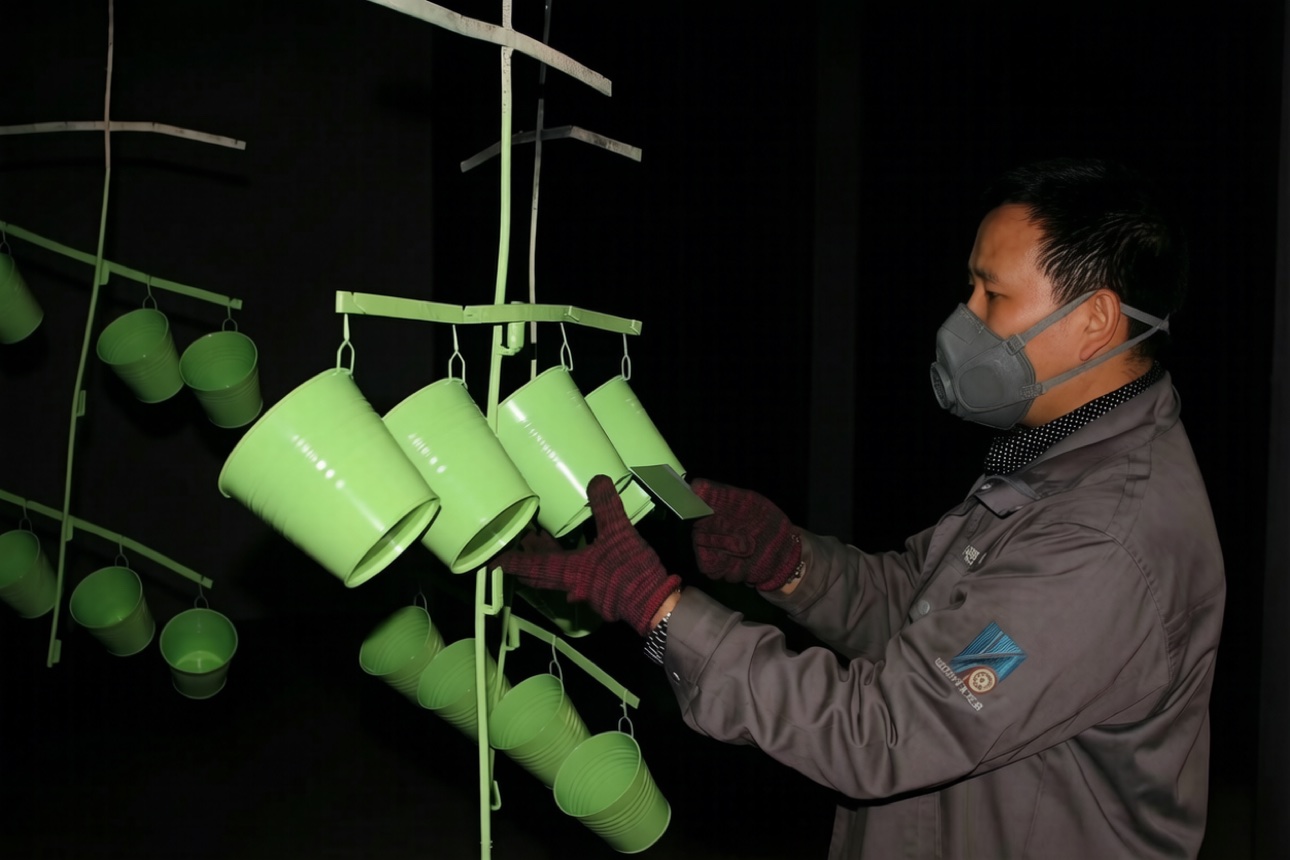Worker inspecting green powder-coated parts for coating quality